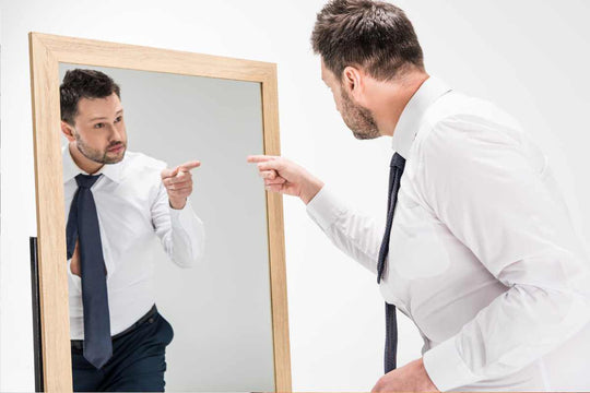 Un homme qui essaie de prendre confiance en lui face à un miroir 